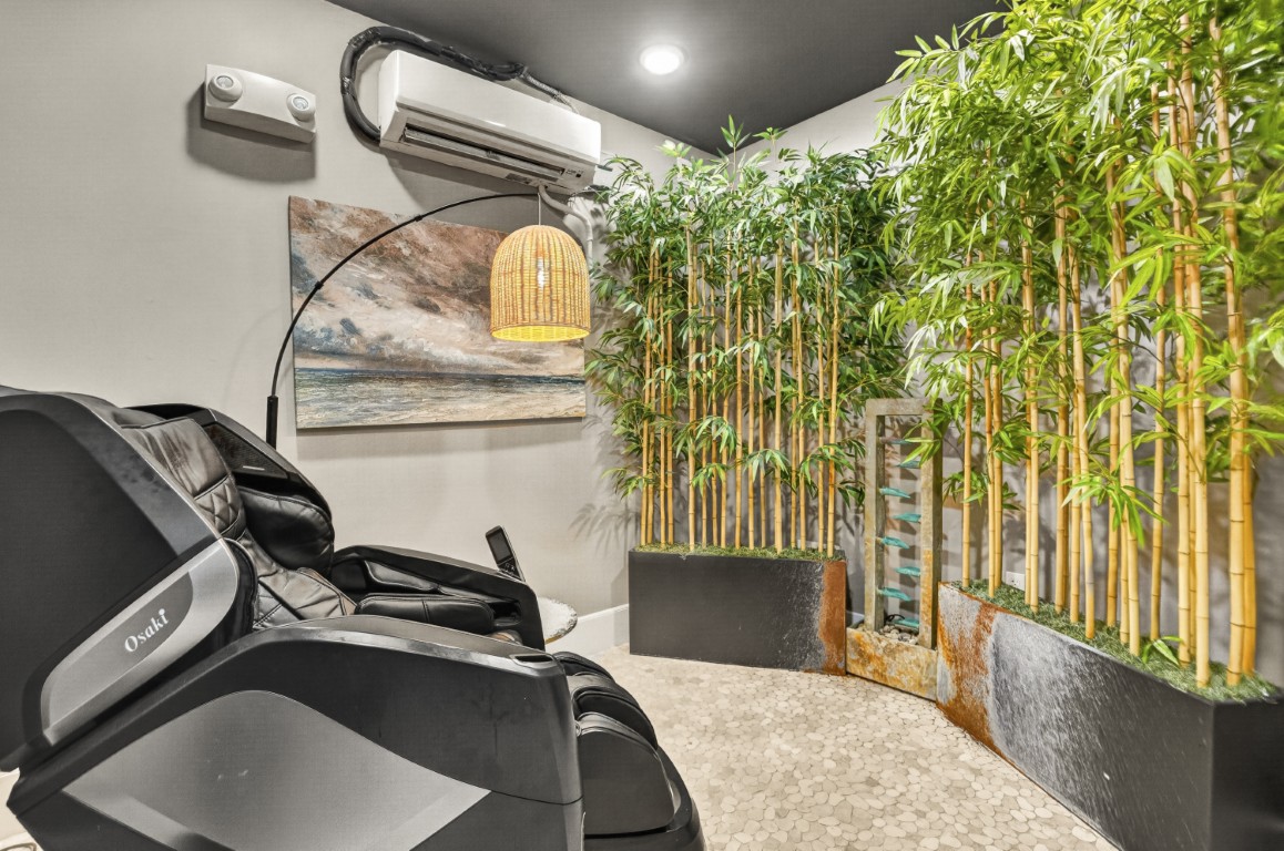 Novus Massage chair in a relaxing room with bamboo plants, a water feature, wall art, and a hanging lamp.